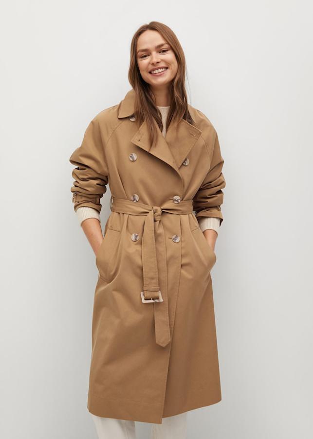 Trench de tejido técnico resistente al agua con patronaje ancho, cuello de solapa, manga larga, trabillas en los puños, cinturón desmontable y cierre de botones en la parte delantera con botones efecto carey, de Mango (79,99 €).