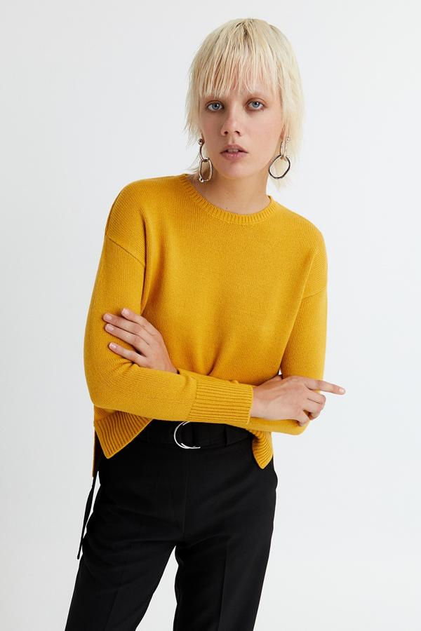 Con cuello perkins y en color amarillo, este jersey cuenta abertura lágrima en la espalda cerrada con un botón. Disponible en otros tonos, tiene un precio de 9,99 euros.