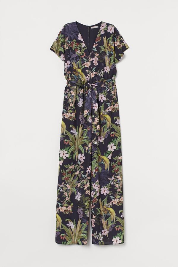 En color azul oscuro con estampado floral, este mono con escote de pico y abertura con botón en la nuca cuenta con cinturón extraíble y perneras ligeramente acampanadas. De manga corta, tiene un precio de 49,99 euros.