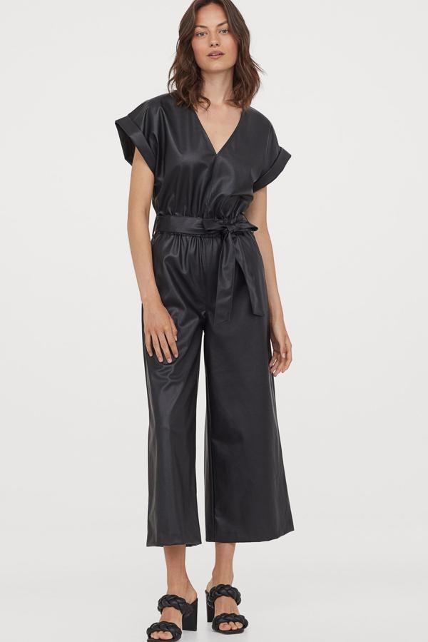 En tejido de piel sintética de color negro, este mono midi con escote de pico y manga corta cuenta con cinturón ancho y cremallera oculta en la espalda. Con perneras amplias rectas, tiene un precio de 49,99 euros