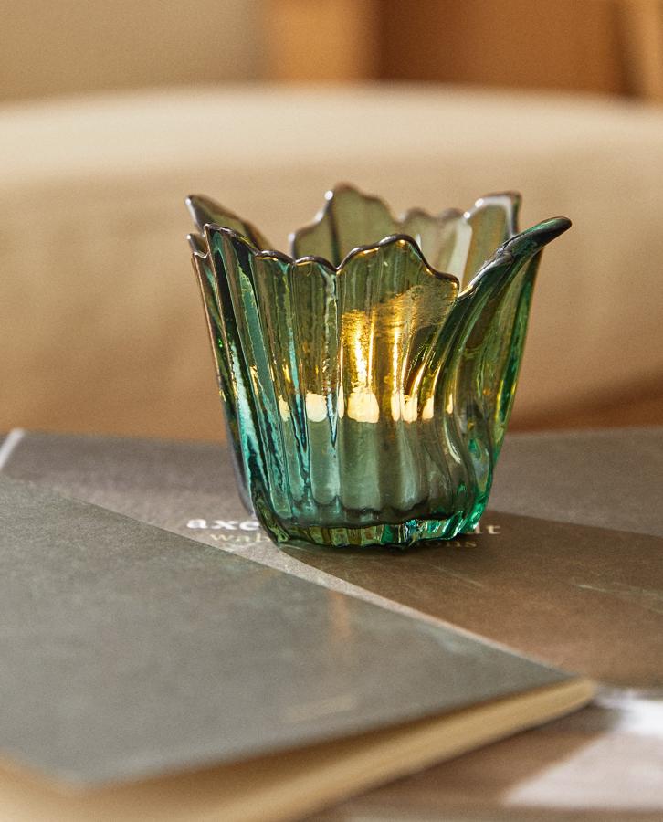 Disponible en color verde o marrón, este portavelas de vidrio con ondas y borde irregular tiene un precio de 3,99 euros.