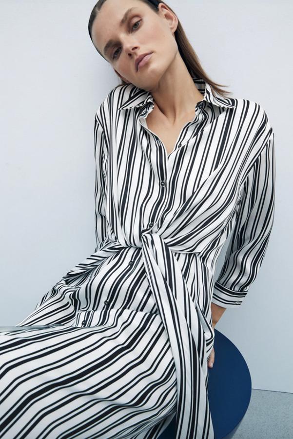 Con cuello solapa y manga tres cuartos acabada en puño y botón, este vestido camisero en crudo con rayas verticales negras viene con detalle de nudo en delantero en el mismo tejido y cierre frontal de botones. Cuesta 39,95 euros y está disponible entre las tallas XS y XL.