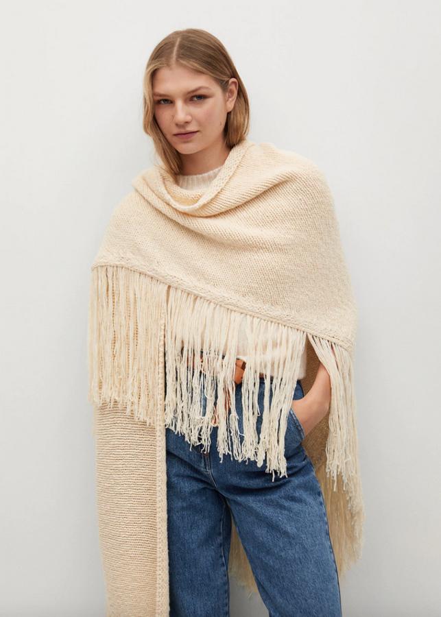 Confeccionado en lana, de color crudo y talla única, este poncho de diseño ancho y largo con terminaciones con flecos cuesta 49,99 euros.
