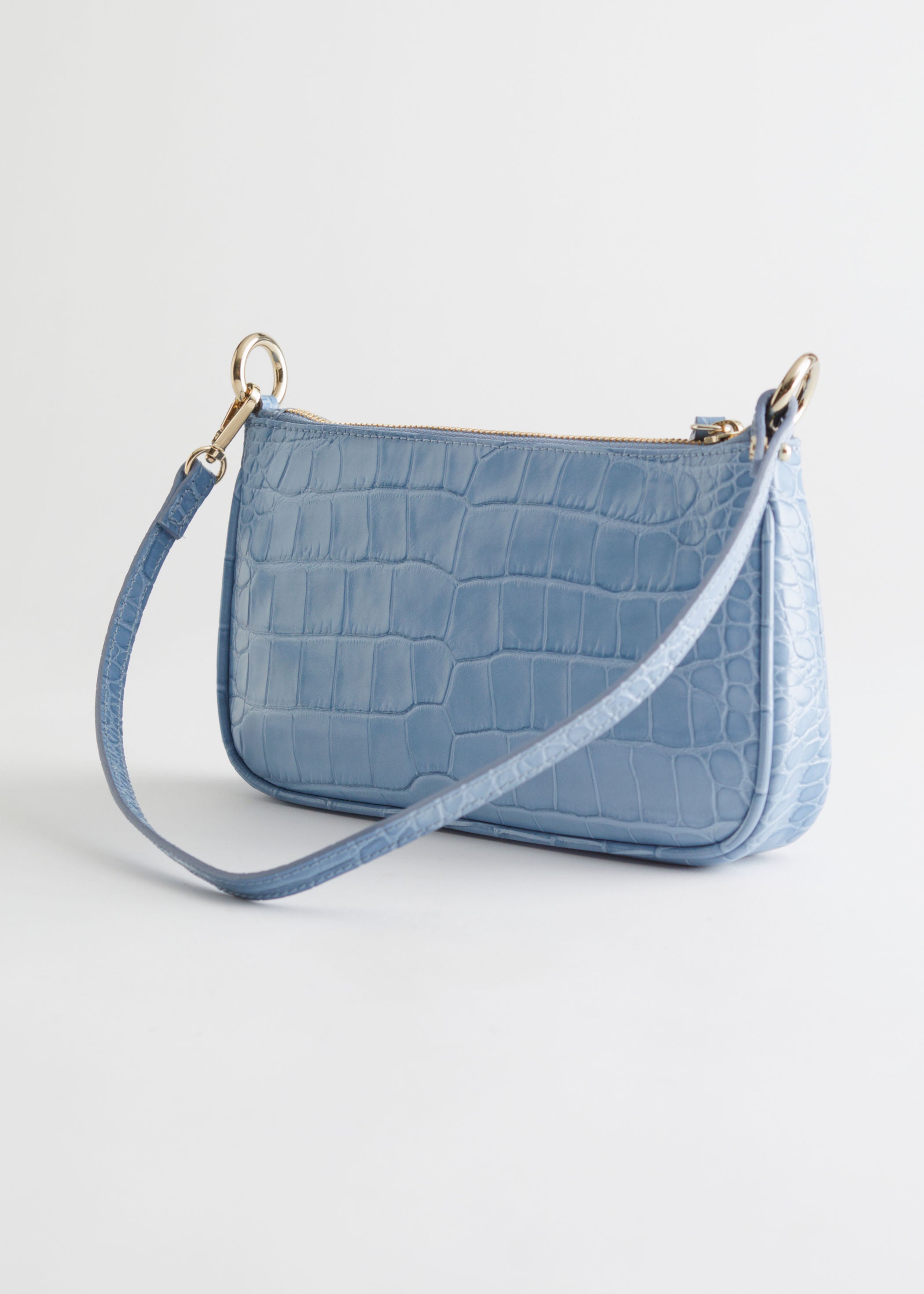 Bolso baguette con grabado de cocodrilo en azul bebé de &Other Stories. (89 euros).