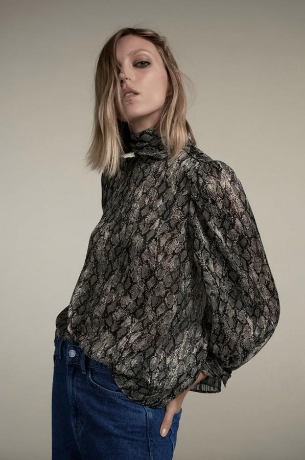De cuello subido y manga larga abullonada acabada en puño con botones es de Zara y está confeccionada con detalle de hilo metalizado y cierre de hombro con botones. Disponible entre las tallas XS y XL, cuesta 25,95 euros.