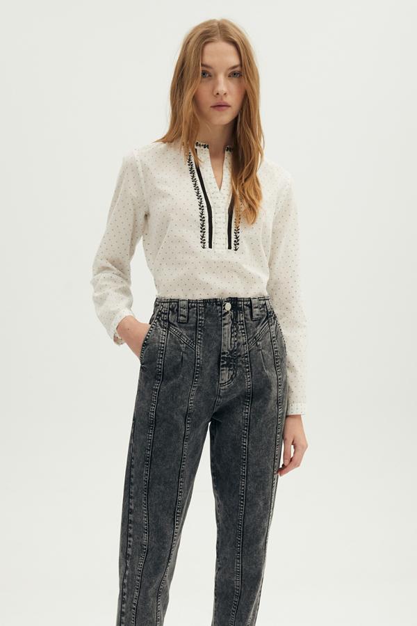 En color blanco roto y con bordados en negro en la parte delantera, esta camisa de manga larga tiene un precio de 13,99 euros.