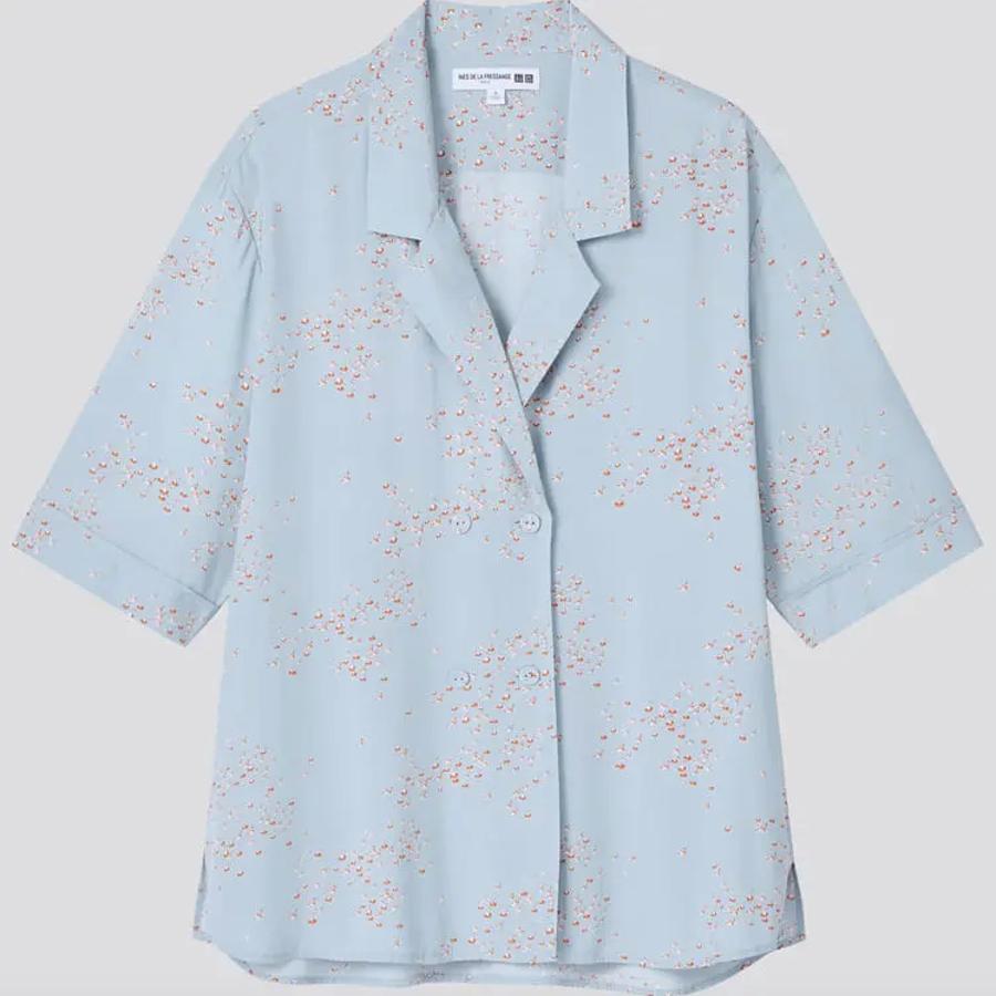 Esta blusa azul celeste con estampado de flores rojas, doble botonadura a tono y cuello clásico con muesca es de manga corta y podremos encontrarla entre las tallas XXS y XXL por 39,90 euros.