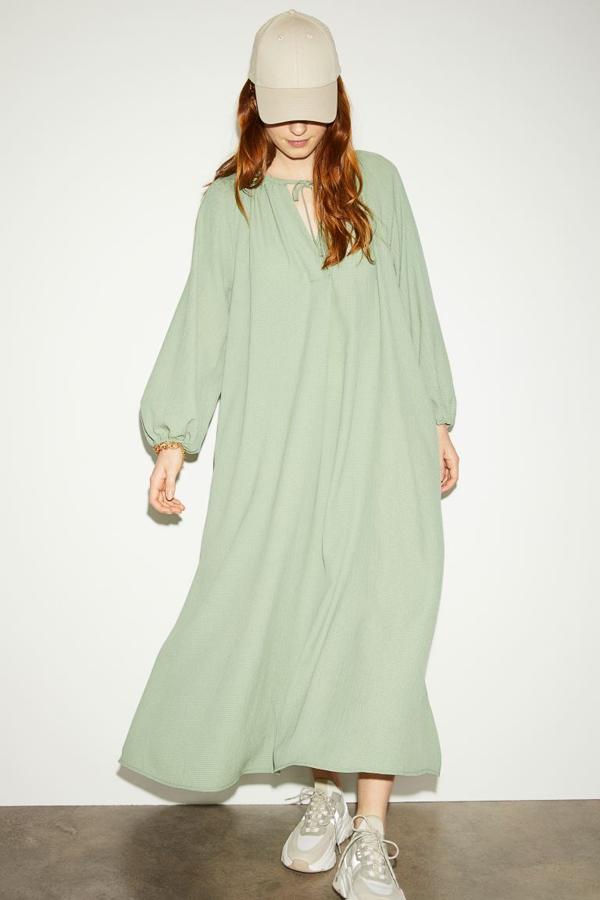 De venta exclusiva en la web de la firma, este vestido midi con vuelo en verde claro viene con cuello redondo fruncido, abertura de pico con lazada en el escote, mangas raglán largas con elástico fino en los puños y bolsillos al bies ocultos. Tiene un precio de 29,99 euros y podemos encontrarlo entre las tallas XS y XXL.