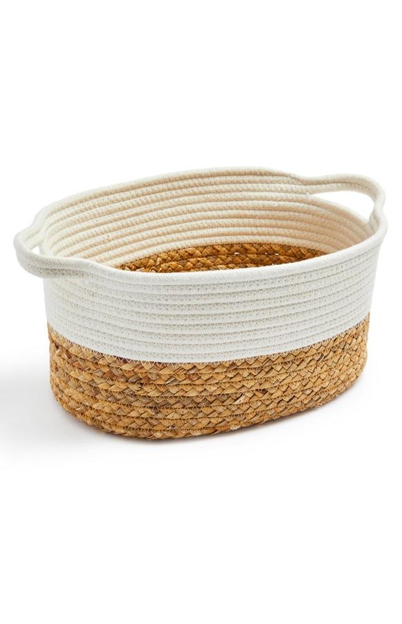 Con diseño ovalado y en material tejido en dos tonos, esta cesta con asas tiene un precio de 10 euros.