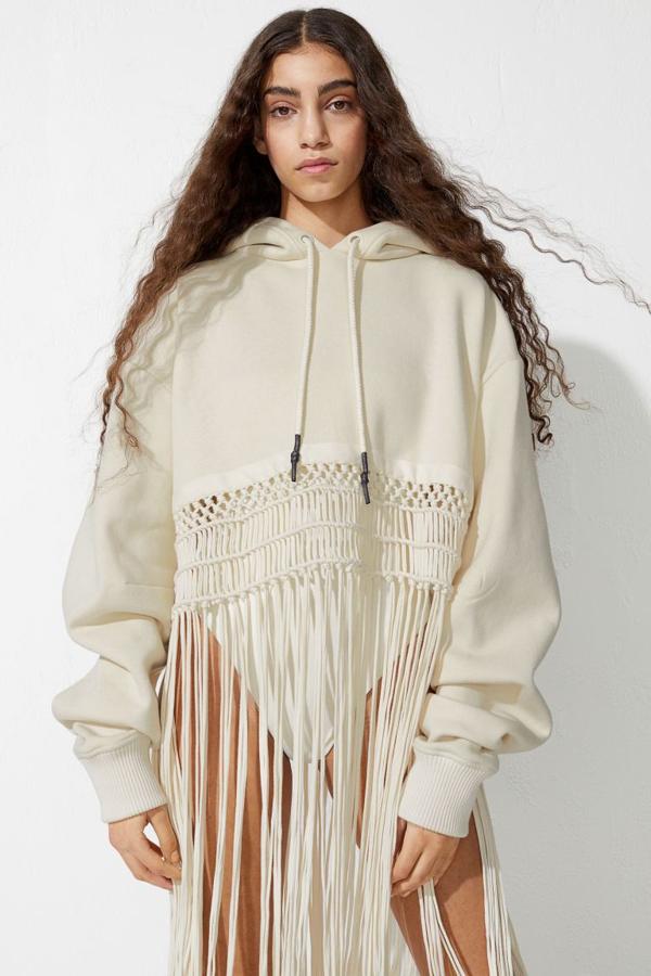 Esta sudadera corta en color crema confeccionada en mezcla de algodón orgánico viene con diseño de hombros caídos, capucha forrada con cordón de ajuste y bajo ancho de macramé con flecos largos. Cuesta 79,99 euros y, de momento, está agotada en todas las tallas.