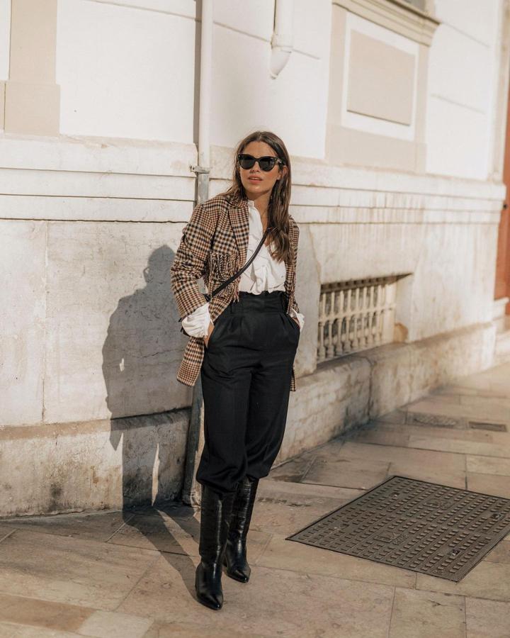 Chaqueta con estampado de cuadros y flecos + pantalón negro + botas altas + camisa blanca (@jessiekass)