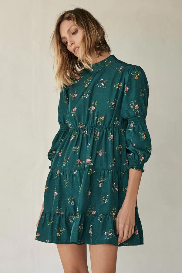 Este vestido mini con cuello subido y manga larga acabada en elástico cuenta con bajo con volantes y cierre en la espalda con abertura y botones. En color verde con estampado de flores, es de Zara y tiene un precio de 29,95 euros.