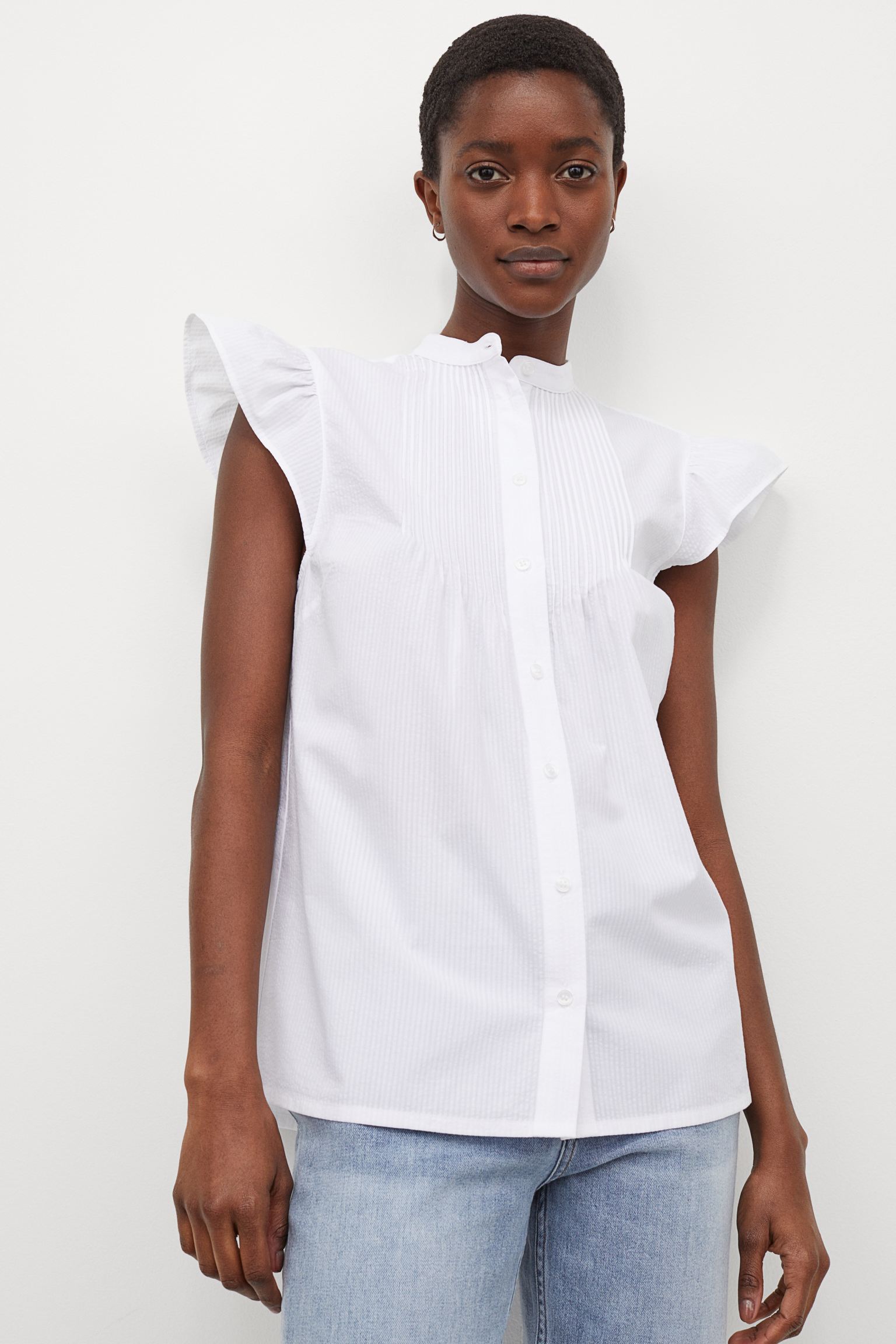 Si la buscas de manga corta, esta camisa vaporosa con cuello mao y jaretas es una opción perfecta para cuando llegue el buen tiempo. (19,99 euros en H&M).