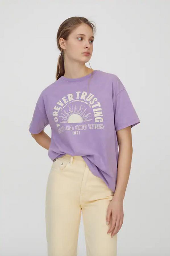 Confeccionada al 100% en algodón, esta camiseta lila con gráfico a contraste en blanco en el pecho viene con mangas cortas y cuello redondo. Cuesta 12,99 euros y está disponible entre las tallas XS y XL.