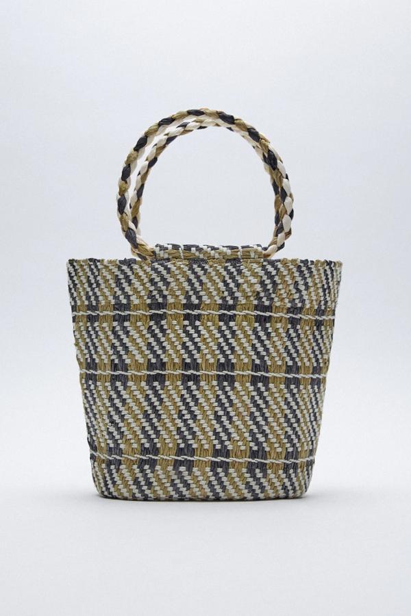 Disponible en tonos verdes o en color dorado, este bolso formato capazo con cuerpo trenzado efecto rafia y asas de mano trenzadas cuenta también un asa de hombro con cadena. Es de Zara y tiene un precio de 22,95 euros.