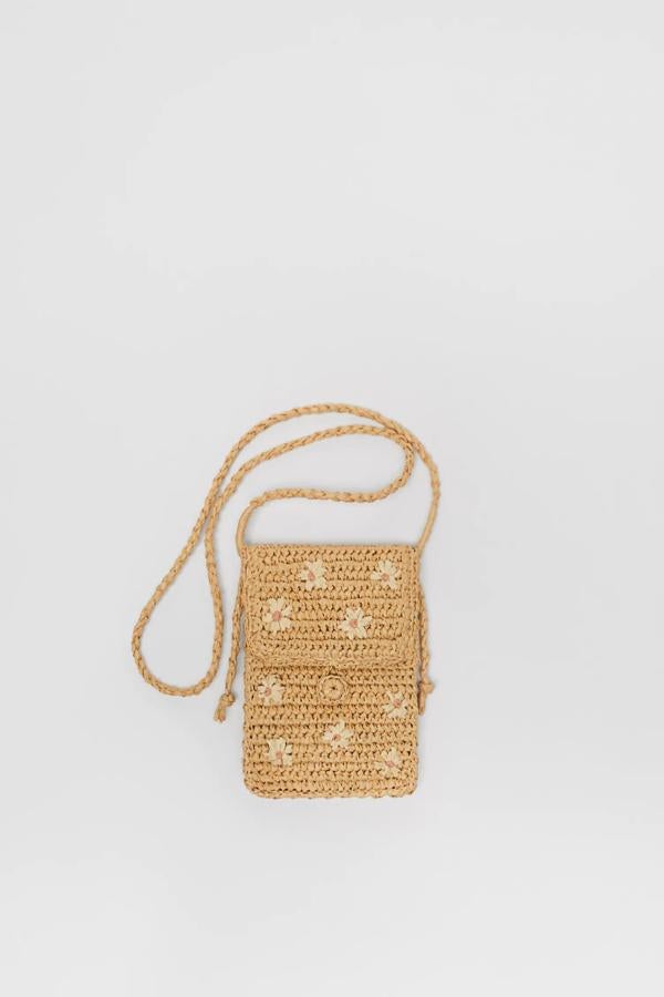 En rafia de color beige, este bolso bandolera de tamaño pequeño con detalle de estampado de flores cuenta con forro interior de algodón y tiene un precio de 13,95 euros. Es de Zara.