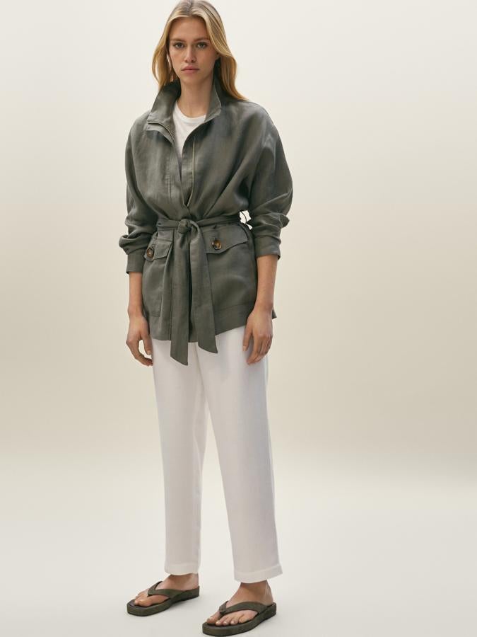Con cuello alto y cierre frontal de cremallera oculta por tapeta, esta chaqueta de lino en color caqui con cinturón a tono y bolsillos laterales de plastrón con solapa está disponible en las tallas S, M y L por 69,95 euros.