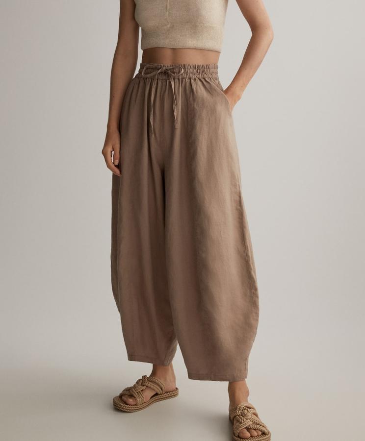 Pantalón silueta harem 100% lino de Oysho: 29,99 euros. En tono tierra, cinturilla elástica y bolsillos laterales.