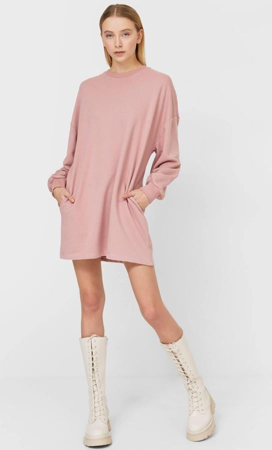 Disponible en rosa, gris marengo, celeste o piedra, este vestido sudadera corto con bolsillos y manga larga acabada en rib es de Stradivarius y tiene un precio de 15,99 euros