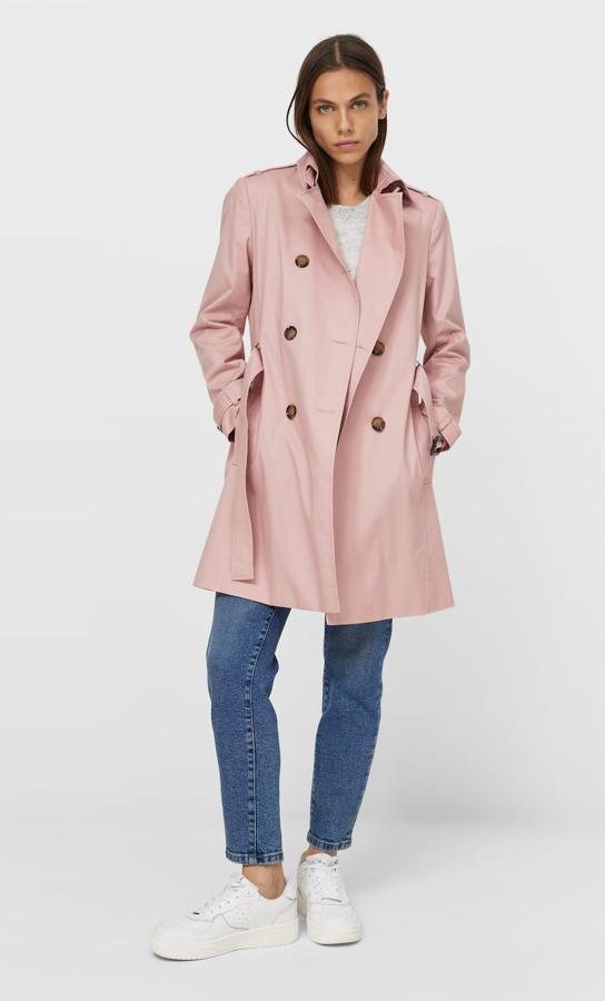 En color rosa empolvado, este trench con manga lagar acabada en puño con trabillas y bolsillos frontales cuenta con cinturón del mismo tejido y tiene un precio de 29,99 euros.