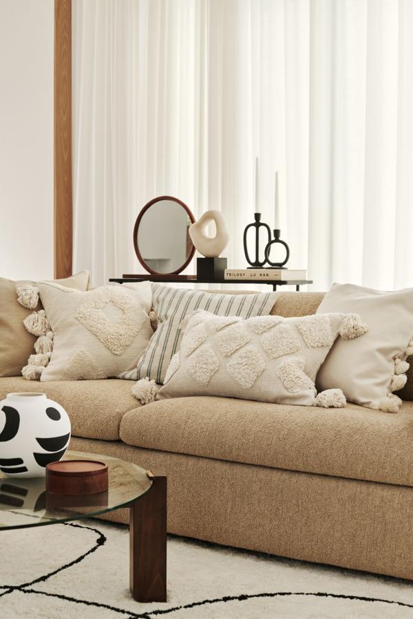 Los cojines beige con textura y grandes borlones de H&M Home cuestan 19.99 euros cada uno.