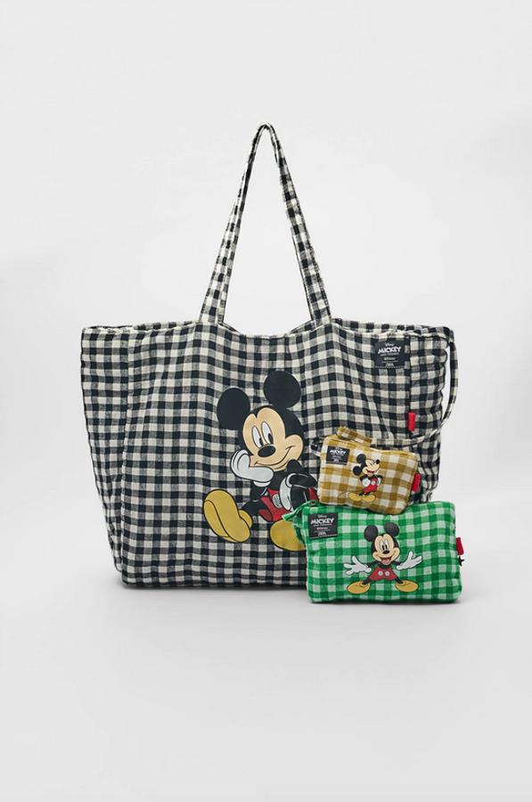Con estampado en blanco y negro y un dibujo de Mickey Mouse en uno de los frontales, este bolso en formato shopper es de Zara y viene con doble de asa de hombro, monedero y estuche en el interior y cierre superior de cremallera. Tiene un precio de 21,95 euros.