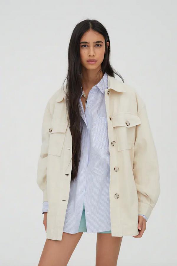 Confeccionada en algodón, esta sobrecamisa de Pull & Bear en color natural, con cuello clásico, cierre de botones frontal a contraste y bolsillos de plastrón en la pechera con solapa y botón y bolsillos laterales ocultos en la costura, tiene un precio de 29,99 euros y está disponible entre las tallas XS y XL.
