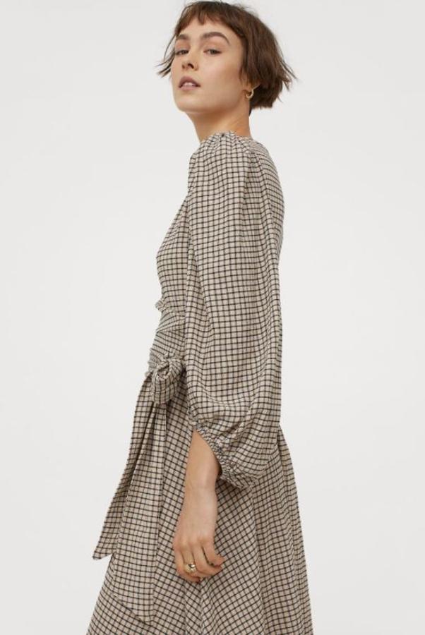 Vestido midi en punto crepé de H&M. Modelo cruzado con escote en pico, mangas globo largas con elástico fino en los puños y lazada ancha en la cintura. Precio: 49,99 euros.