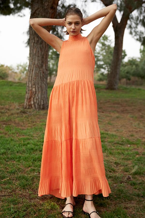 En un favorecedor color naranja, este vestido midi con cuello halter y cierre con botones en la nuca tiene un precio de 39,99 euros.