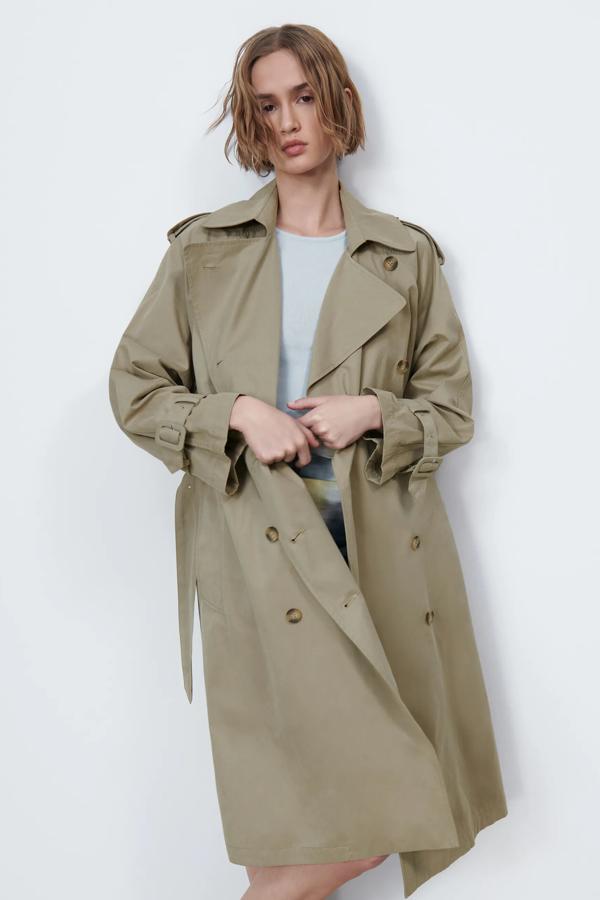 En color tostado, este trench con cuello solapa y cinturón con hebilla cuenta con bolsillos laterales y cierre frontal cruzado con botones. Es de Zara y tiene un precio de 59,95 euros.
