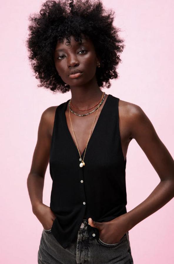 Esta camiseta con escote de pico y manga sisa tiene un cierre frontal con botones. Además de en negro, también está disponible en blanco y en beige. Su precio es de 12,95 €.