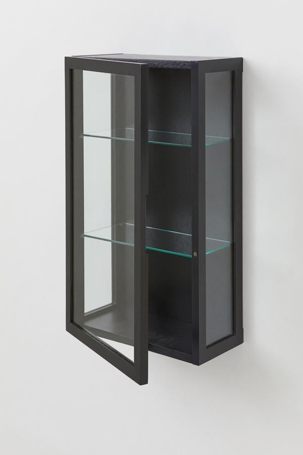 En madera de color negro, este armario de pared con puerta y dos estantes de cristal tiene unas medidas 70x40x21, 3 centímetros y un precio de 149 euros.