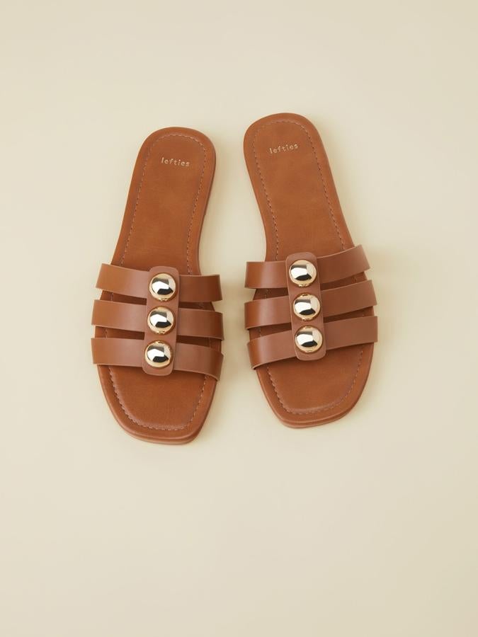 Estas sandalias de tiras en color cuero con detalles metálicos también están disponibles en negro. Precio: 19.99 euros en Lefties.