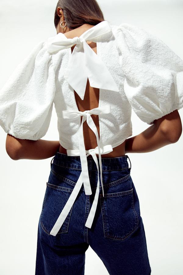 Con escote cuadrado y abertura trasera con lazadas, este top blanco de mangas abullonadas hasta el codo tiene un precio de 25,99 euros y está disponible en las tallas S, M y L.