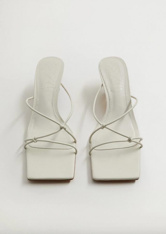 En blanco roto, con tiras de nudos decorativos, estas sandalias blancas de Mango con punta cuadrada y tacón fino de cinco centímetros forrado cuestan 29,99 euros y están disponibles entre los números 36 y 40.