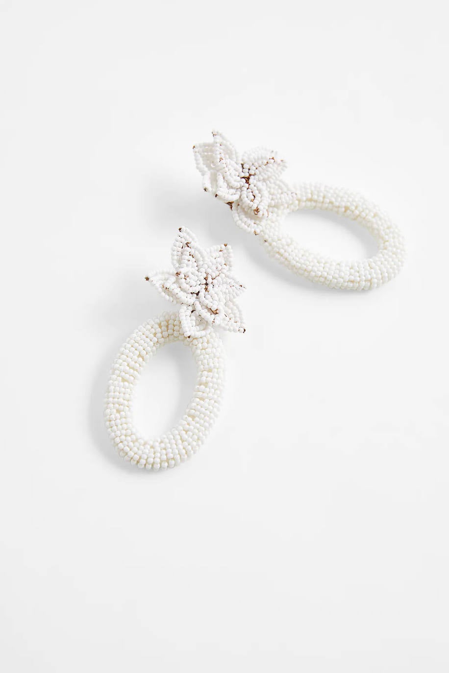 Estos pendientes colgantes están hechos de vidrio. Su acabado de abalorios blancos forma una bonita flor. En cuanto al cierre, es de tuerca y clip, lo que resulta muy cómodo. ¿Te gustan? Pueden ser tuyos por 9,95 €.