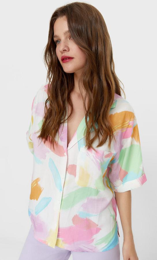 En tonos pastel de rosa, naranja, verde y azul sobre blanco, esta camisa de cuello y solapa con escote de pico, manga corta, bolsillo de plastrón en la pechera y cierre frontal de botones a tono es de Stradivarius y podemos comprarla por 15,99 euros entre las tallas XS y XL.