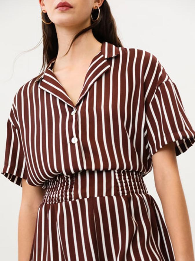 Estampado de rayas blancas sobre marrón para esta camisa de Lefties de corte holgado con cuello camisero y manga corta que está confeccionada en tejido satinado. Disponible entre las tallas S y XL, tiene un precio de 12,99 euros.