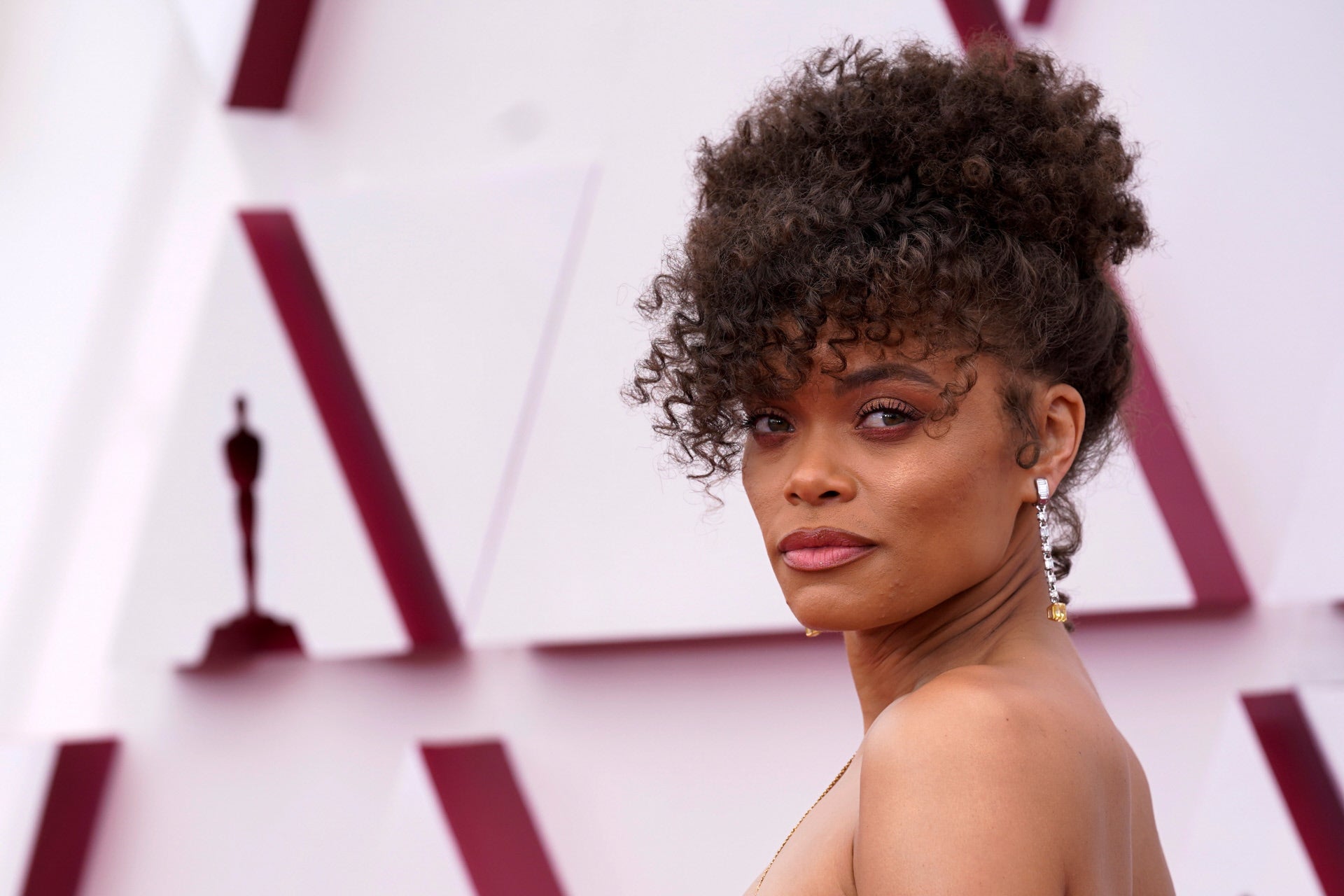 Hemos hablado tantas veces del flequillo para el pelo rizado, que no podíamos dejar escapar el look de belleza de Andra Day en los Oscars 2021. La actriz ha llevado su melena natural en un recogido ochentero con flequillo que nos encanta.