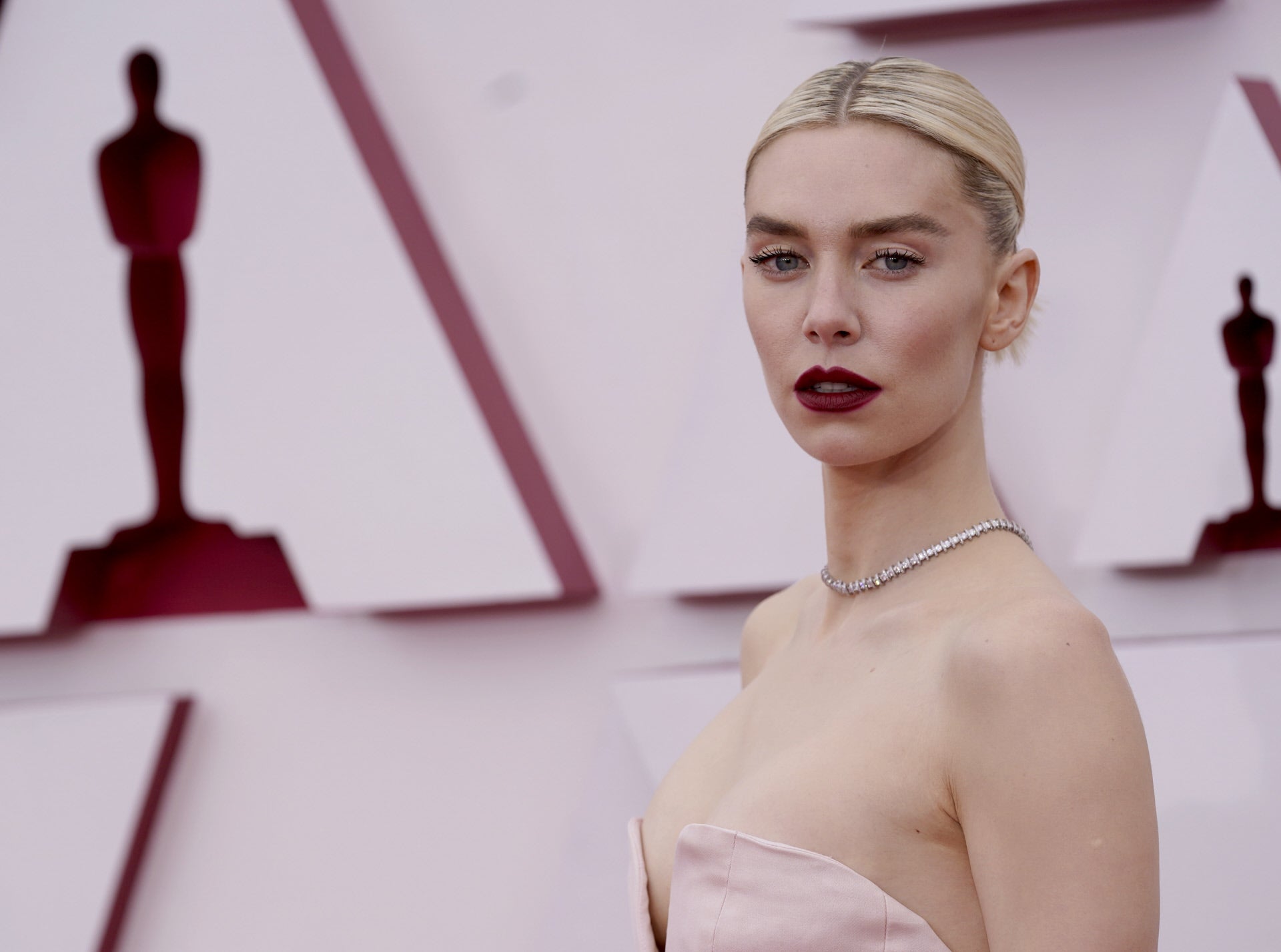 Nos encanta el contraste del looks de belleza Vanessa Kirby: pelo rubio platino recogido con raíces oscuras, pestañas muy marcadas y labios burdeos.