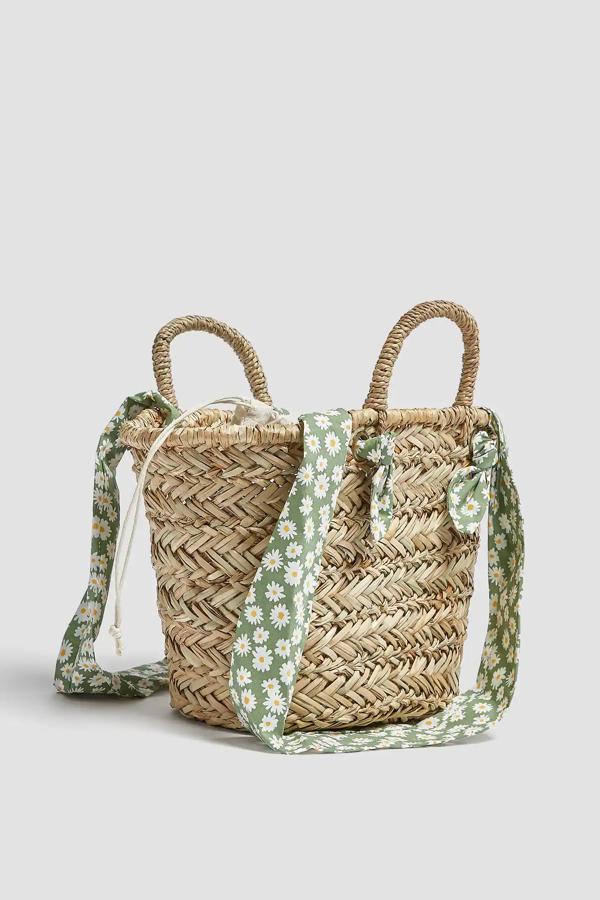 Este bolso tipo capazo de rafia con asas de hombro tipo pañuelo con estampado de margaritas tiene un precio de 22,99 euros.