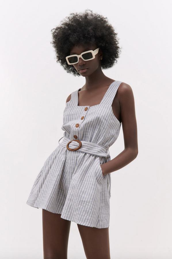 En color azul grisáceo con estampado de rayas blancas verticales, este mono corto de Zara confeccionado con tejido de mezcla de algodón y lino viene con escote recto y tirantes anchos. Con cintura elástica y cinturón a tono con hebilla de madera, tiene cierre frontal de botones combinados a contraste. Podemos encontrarlo entre las tallas XS y XL por 29,95 euros.