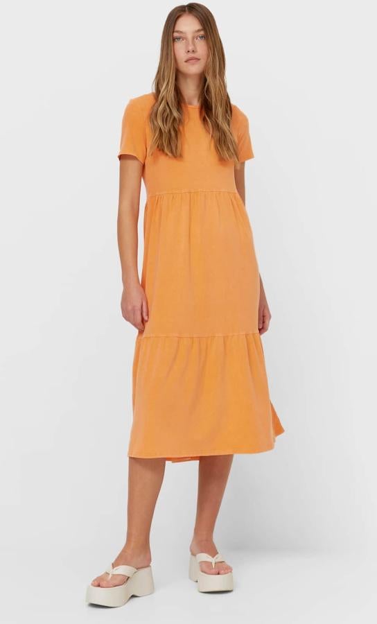 Disponible en naranja o en rosa, este vestido midi con cuello redondo y manga corta cuenta con volante en el bajo y tiene un precio de 19,99 euros.