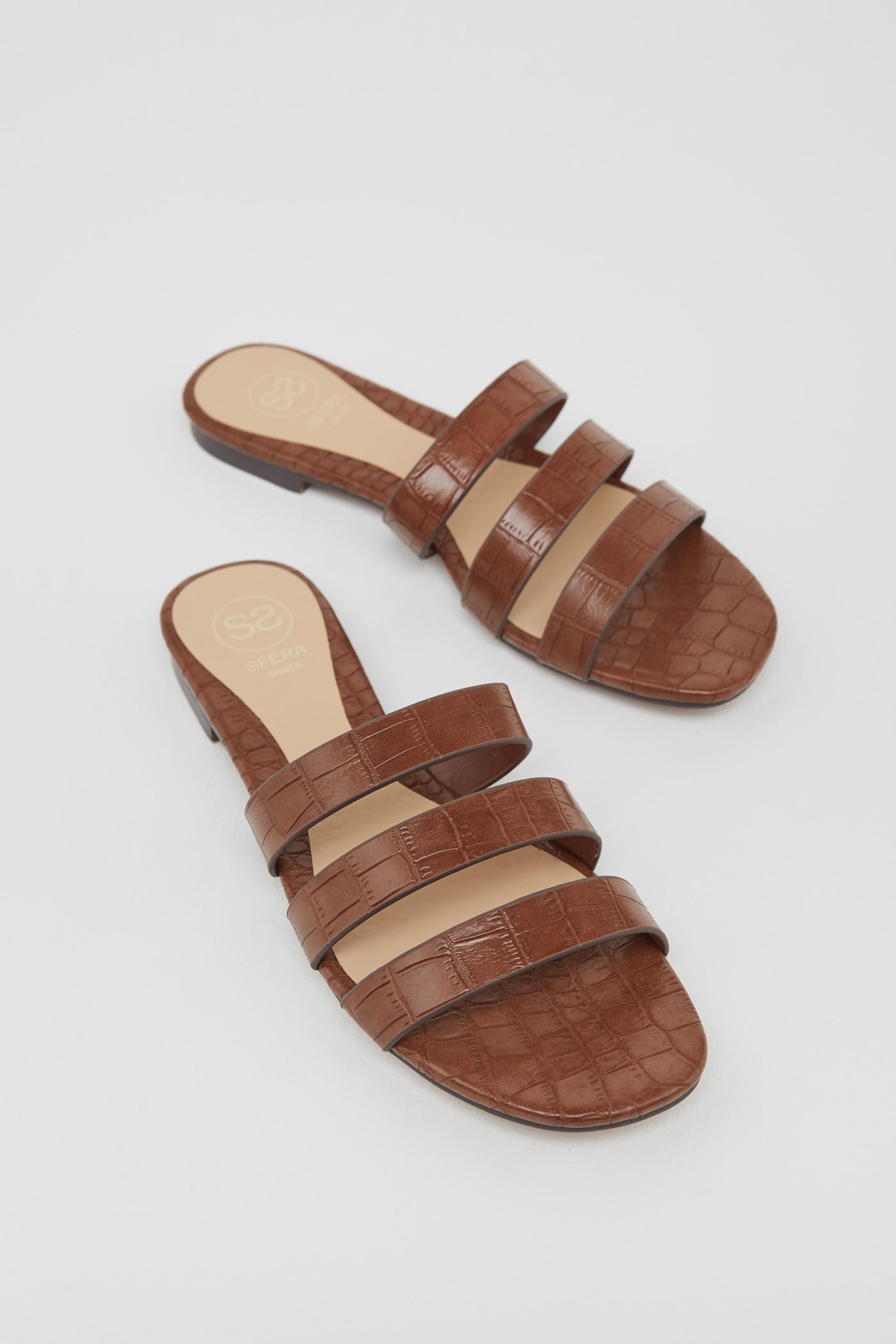 Sandalias con estampado efecto cocodrilo en color marrón. Un tono tendencia que sienta de maravilla con el blanco y el denim. (17,99 euros).