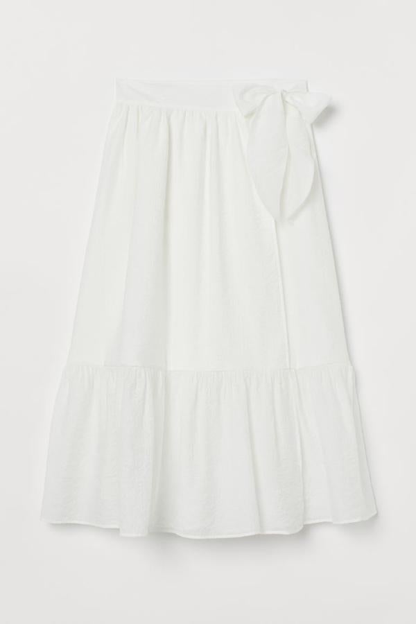 En mezcla de viscosa, de talle alto con pretina ancha de doble capa y botones ocultos y lazo decorativo en un lateral, esta falda midi de H&M en color blanco viene con fruncidos en la cintura que crean un suave drapeado y costura fruncida en la rodilla. Con forro interior de poliéster reciclado, cuesta 29,99 euros y está disponible entre las tallas 32 y 50.
