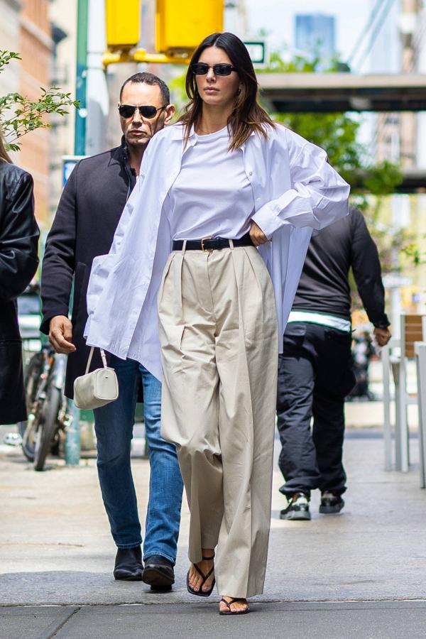 Kendall Jenner pasea por Nueva York con un look de camisa blanca, camiseta, cinturón fino de cuero, pantalones de pinzas de cintura alta y sandalias de tiras de tacón kitten, todo de The Row.