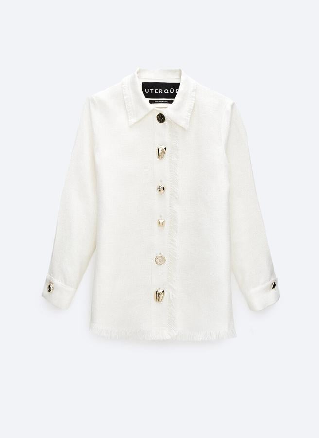 Camisa blanca de manga larga con detalles desflecados y botones dorados, de Uterqüe (129 €).