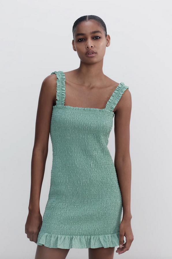 Confeccionado con al menos un 25% de poliéster reciclado, este vestido mini en verde lavado de Zara viene con tirantes anchos fruncidos, cuerpo en nido de abeja, escote recto y bajo acabado en volante. Cuesta 22,95 euros y está disponible entre las tallas S y XXL.