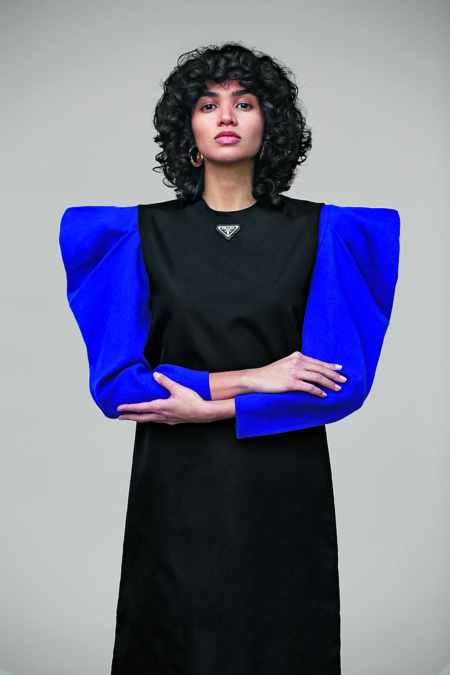 Vestido sin mangas de nylon, de Prada; jersey de punto con hombreras, de Uterqüe; y pendientes de Alighieri. Estilismo: Sandra Solé.