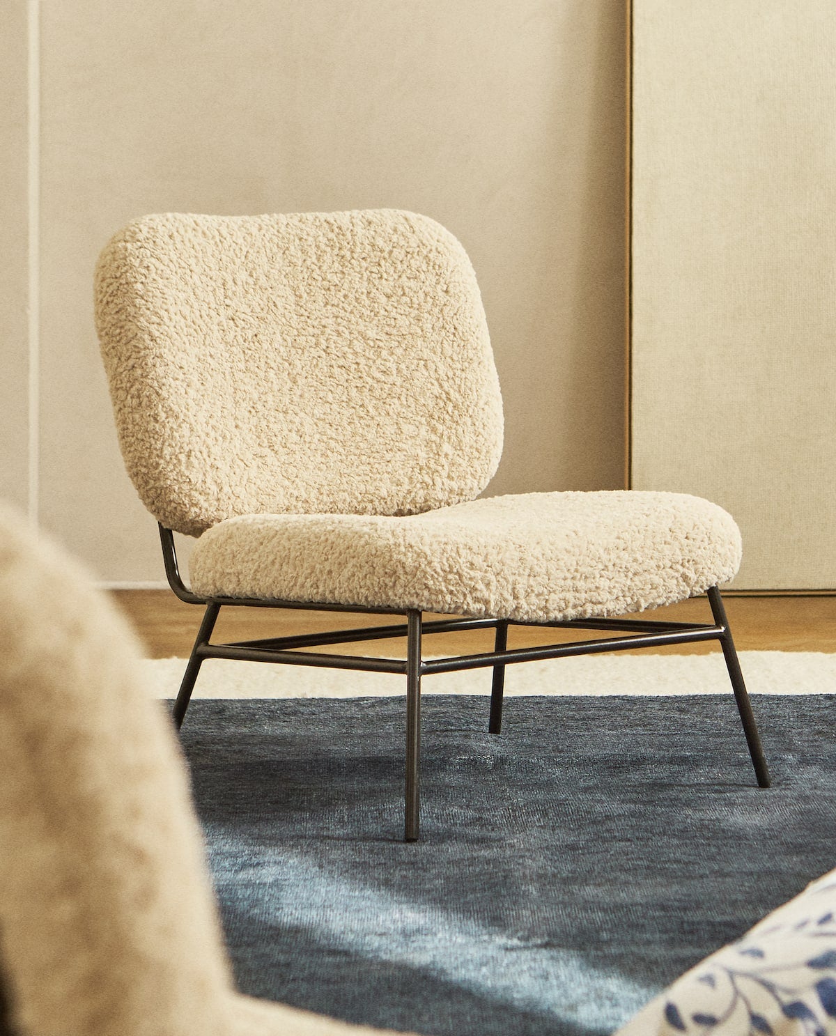 Butaca con estructura metálica en negro mate y tapizada con tejido de efecto borreguito en un color crudo super favorecedor. ¡Un auténtico capricho! (179 euros).